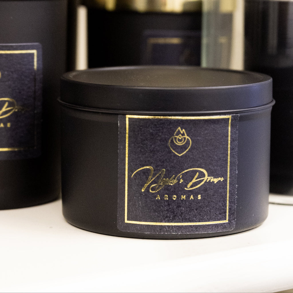 Black candles with gold labels on a white surface