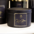 Black candles with gold labels on a white surface