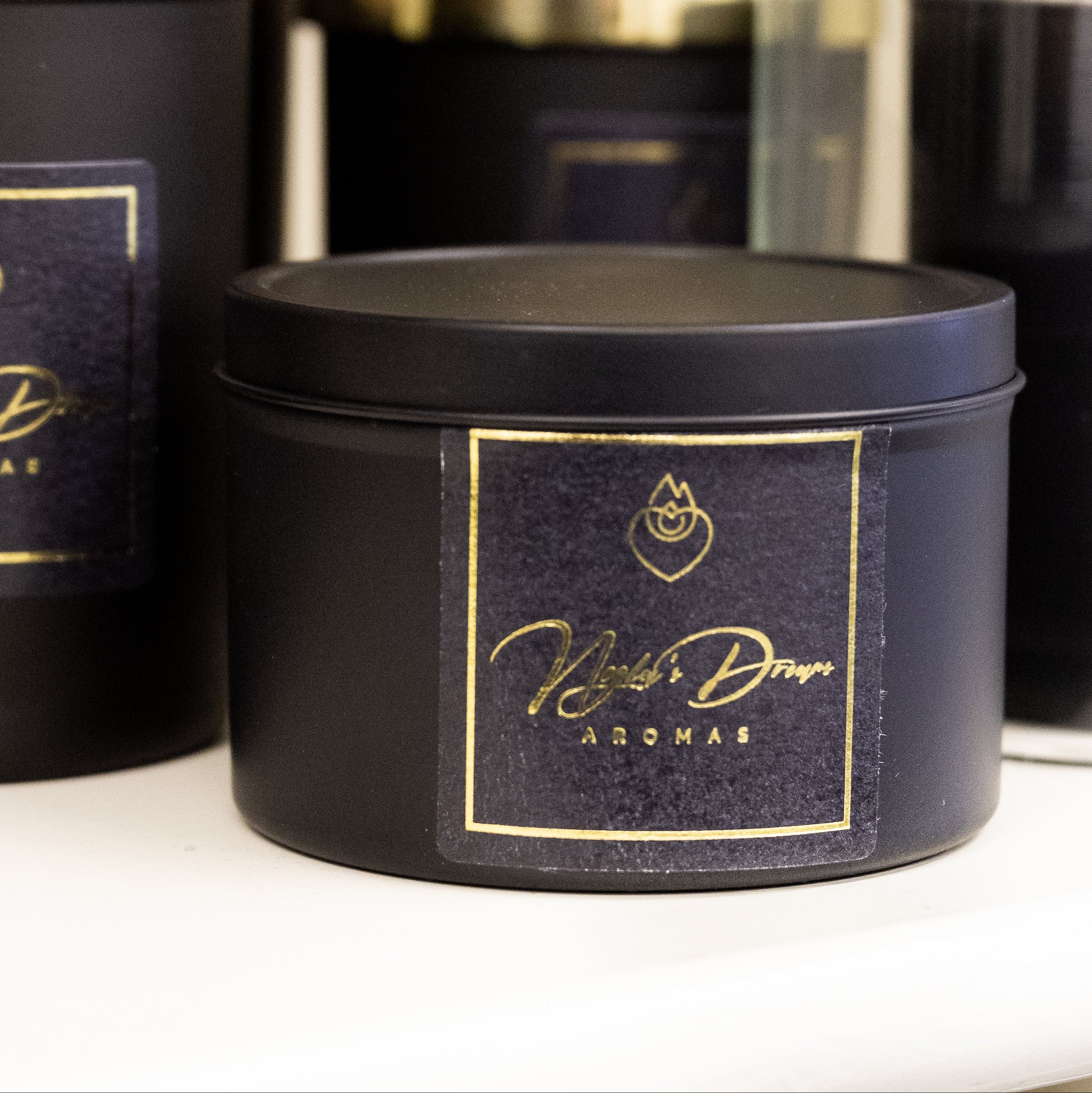 Black candles with gold labels on a white surface