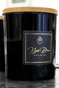 Black candle with a gold label on a dark surface