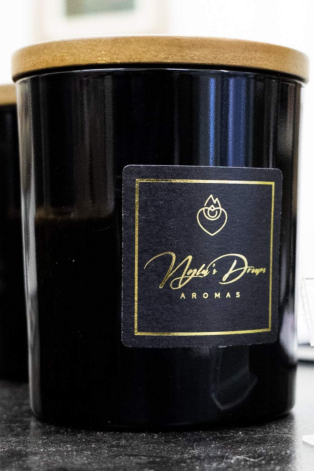 Black candle with a gold label on a dark surface